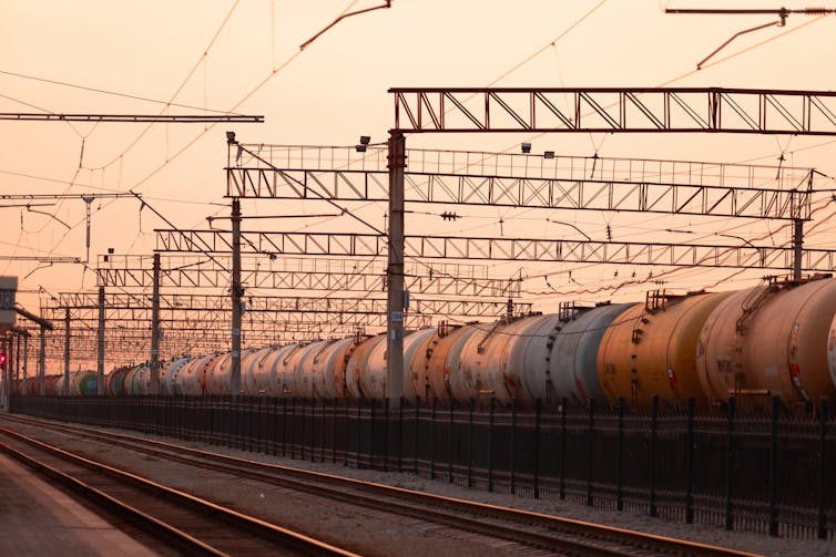 A freight train parked at a train station as dusk falls.