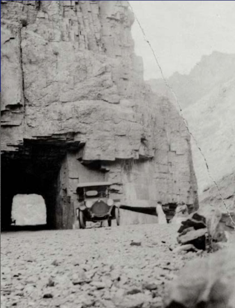 Early 1900s car traveling in the Rocky Mountains.