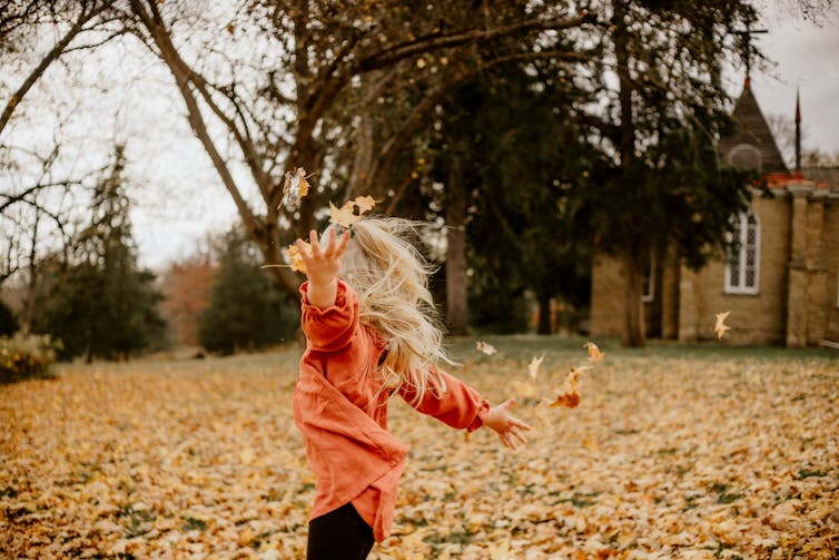 A child twirls in autumn leaves