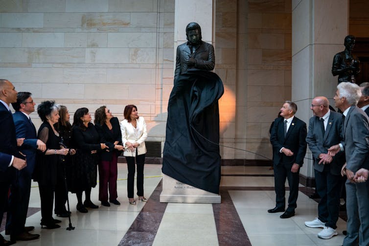 A crowd of people gather around a statue.