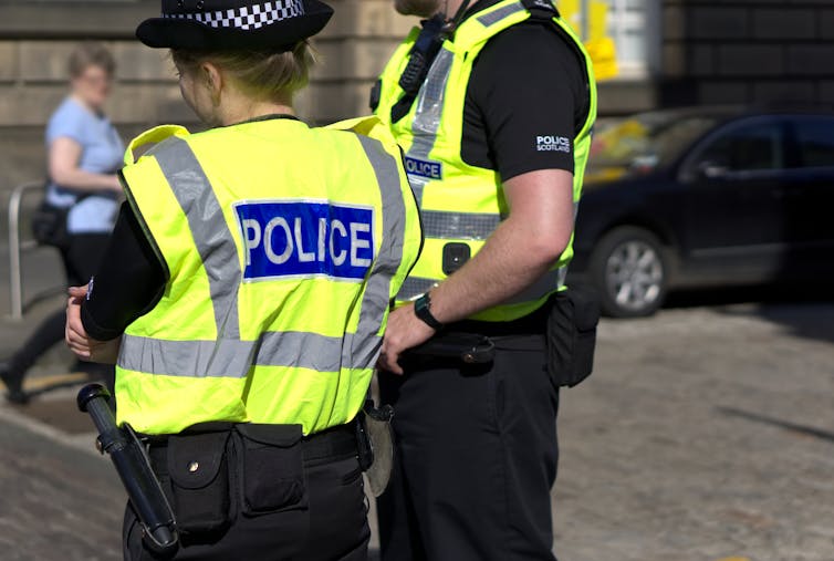 two police officers on duty in hi-vis vests and police scotland shirts