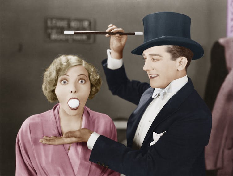 Magician makes an egg come out of a woman's mouth.