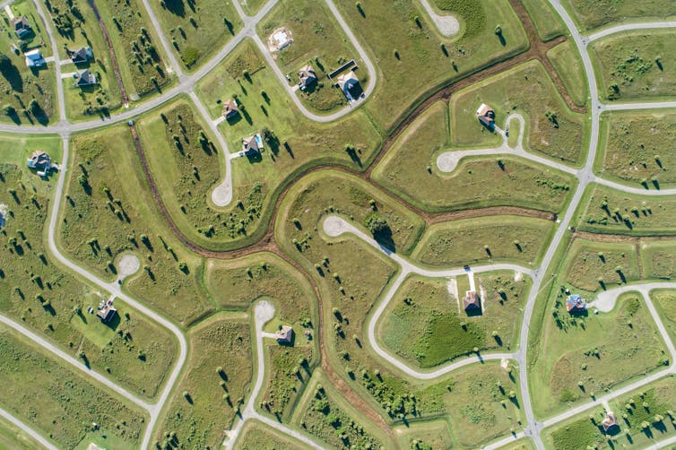 Aerial shot of green area with roads and a low-density housing development