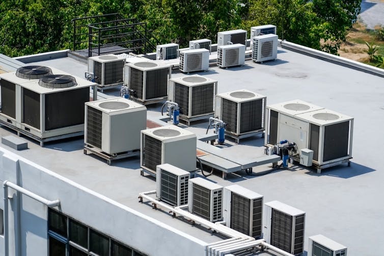 Multiple external units of air conditioning and ventilation systems installed on the roof of a large building.