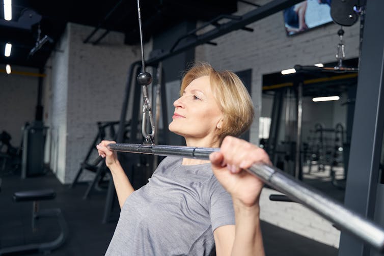 Woman using lat pulldown machine in gym