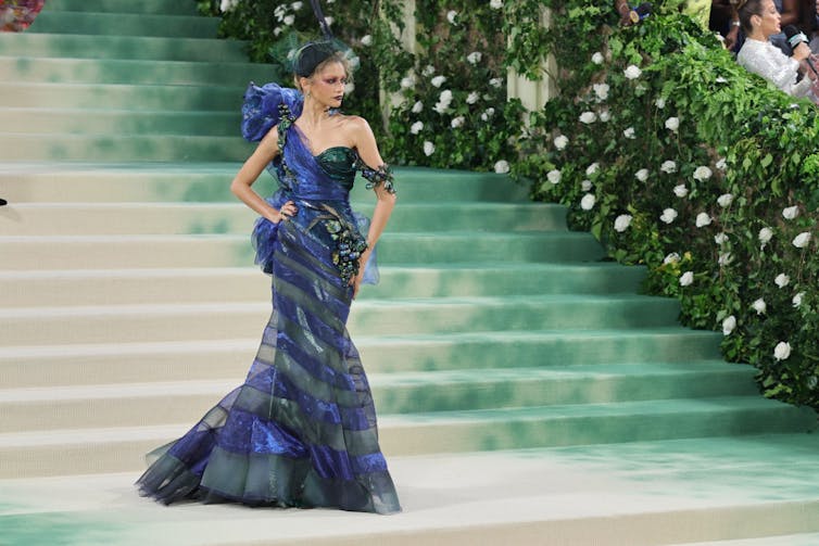 Young woman poses while wearing a purple, blue and green dress.