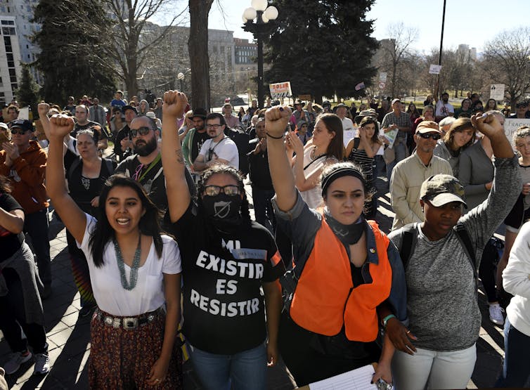 A group of young people march together, holding their fists in the air.