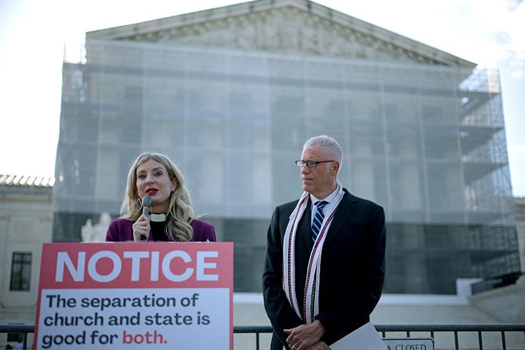 A woman speaks and a man listens during a news conference outside the U.S. Supreme Court