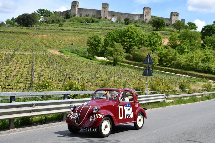 vintage fiat topolino driving through the italian countryside