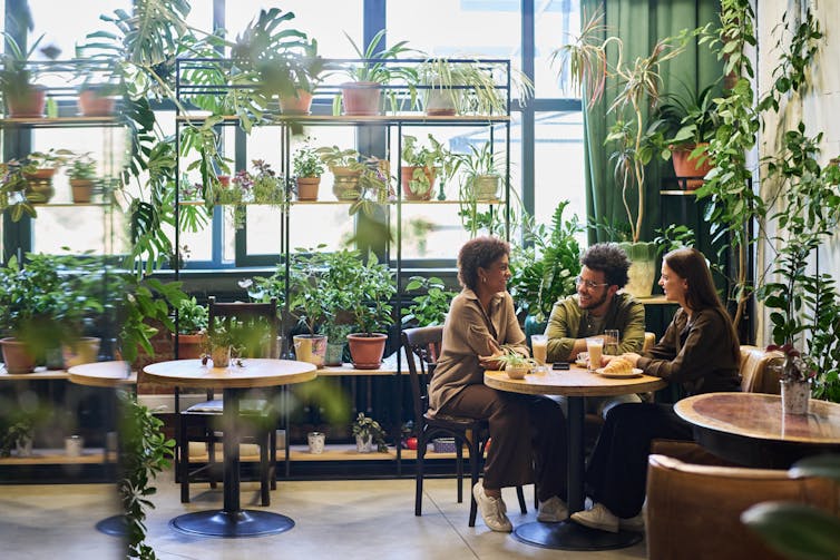 Three people sitting around a cafe table having a conversation