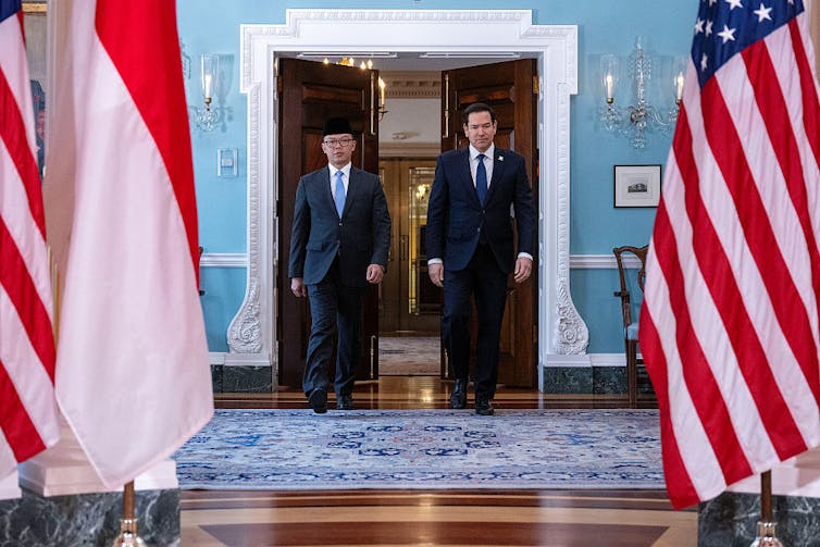 Two men in suits walk towards the camera.