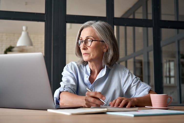 Serious mature older adult woman watching zoom meeting
