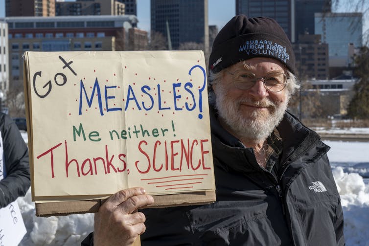 Man holding sign saying, 'Got measles? Me neither! Thanks Science'