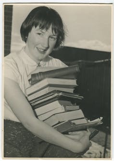 Young Beatrice carrying a stack of books.