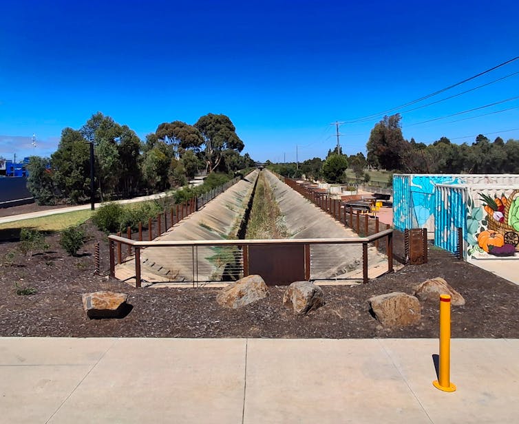 A linear park formed around a disused sewer main in the west of Melbourne, showing a bike path and new community infrastructure.