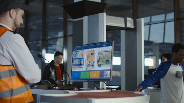 airport customs official looking at bag scans at security