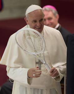A man in white holds a tennis racket