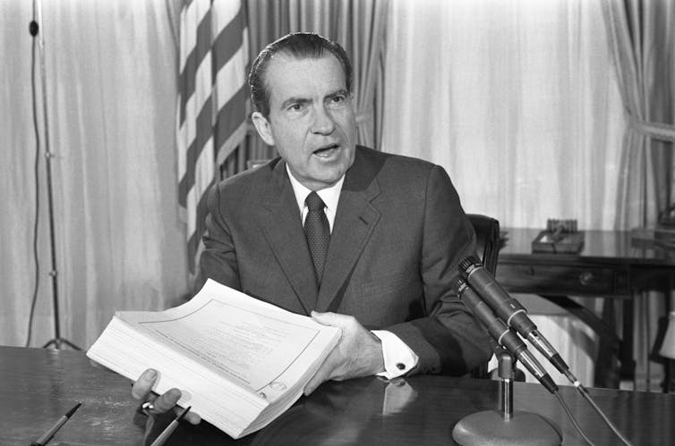 Nixon holds a large document.