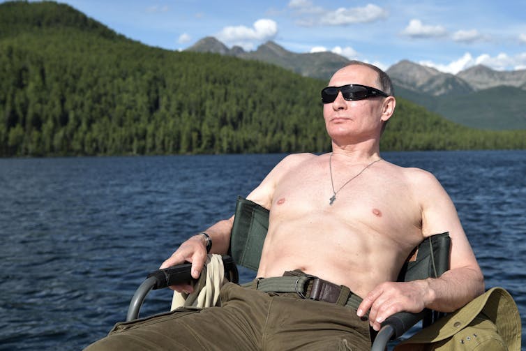 A shirtless man sunbathes.