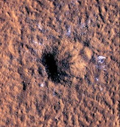 A satellite photo of a crater in red ground.