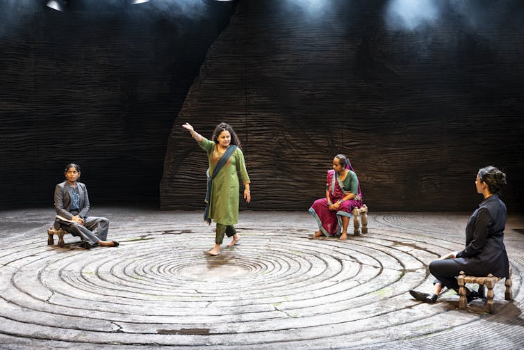Two women in suits and two women in sarees talk.