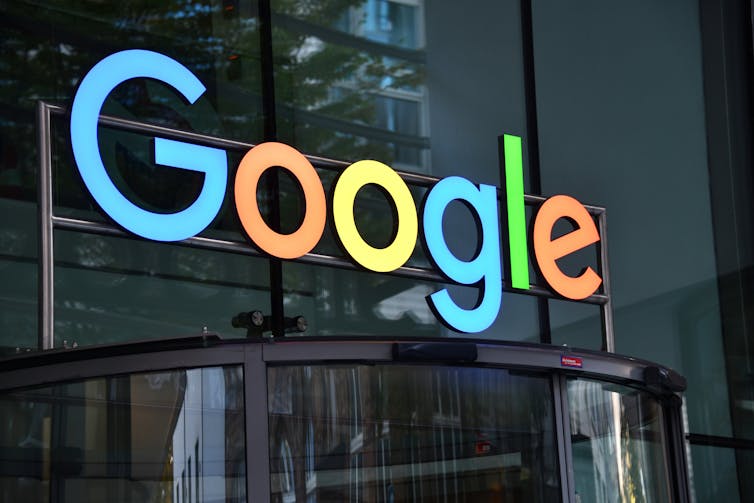 Google's blue, red, yellow and green sign seen on the facade of a building.