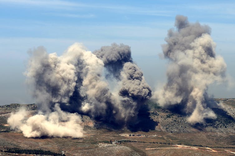 Plumes of smoke rise from explosions.