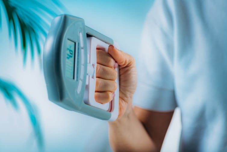 A person squeezes a dynanometer with their hand to measure their grip strength.