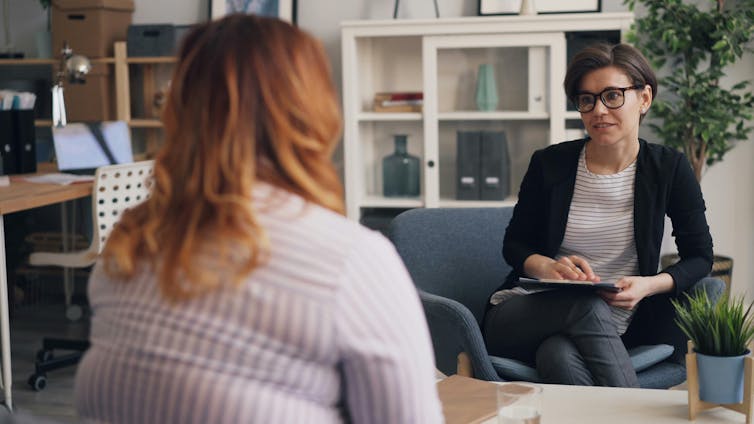a larger woman in office across from a smiling woman who looks like a doctor