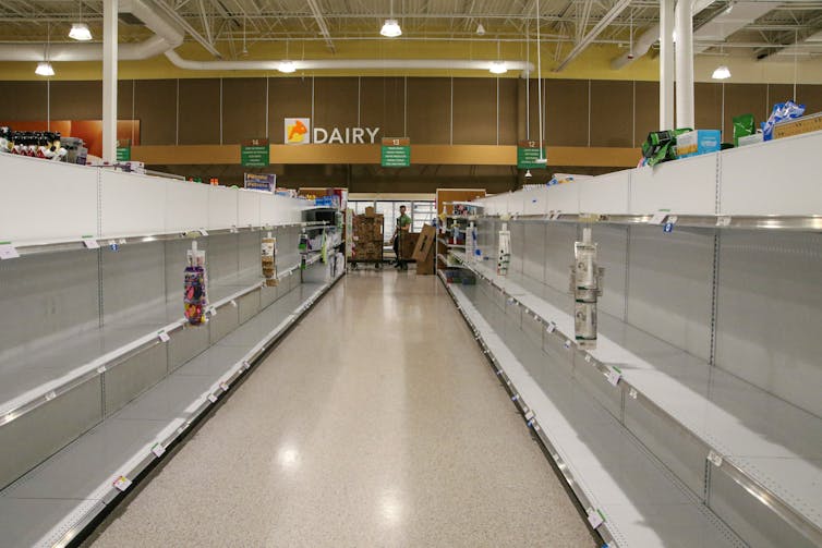 A supermarket aisle with empty shelves on both sides